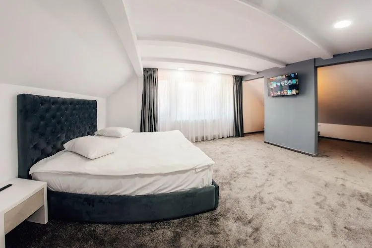 Cameră mare cu pat rotund și tavan cu grinzi