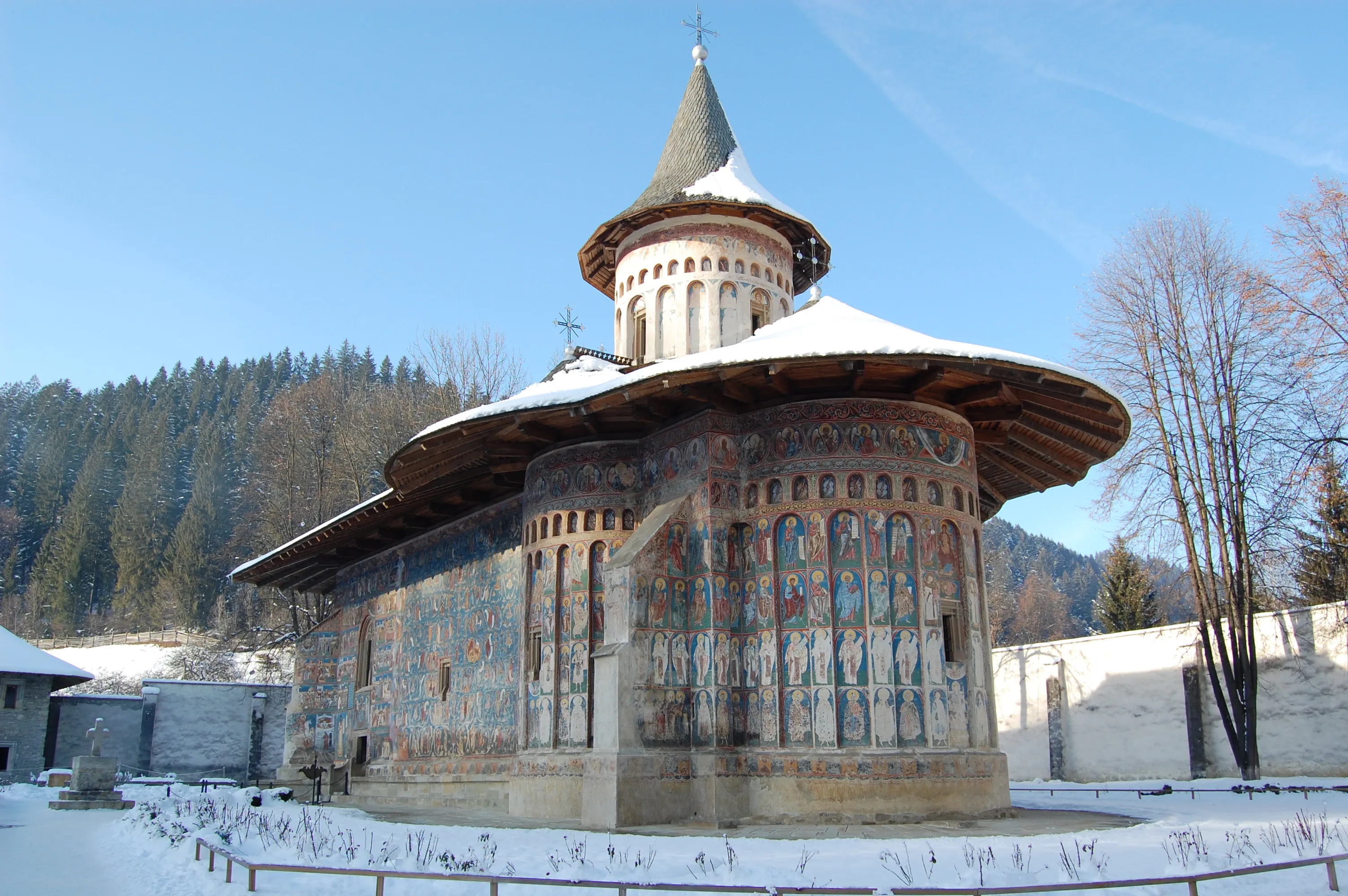 Biserica pictată a Mănăstirii Voroneț, cu turnul moldovenesc și pereții în albastru, iarna